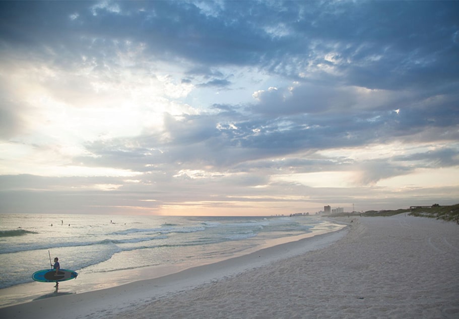 person on the beach holding surfboard on destin florida beach